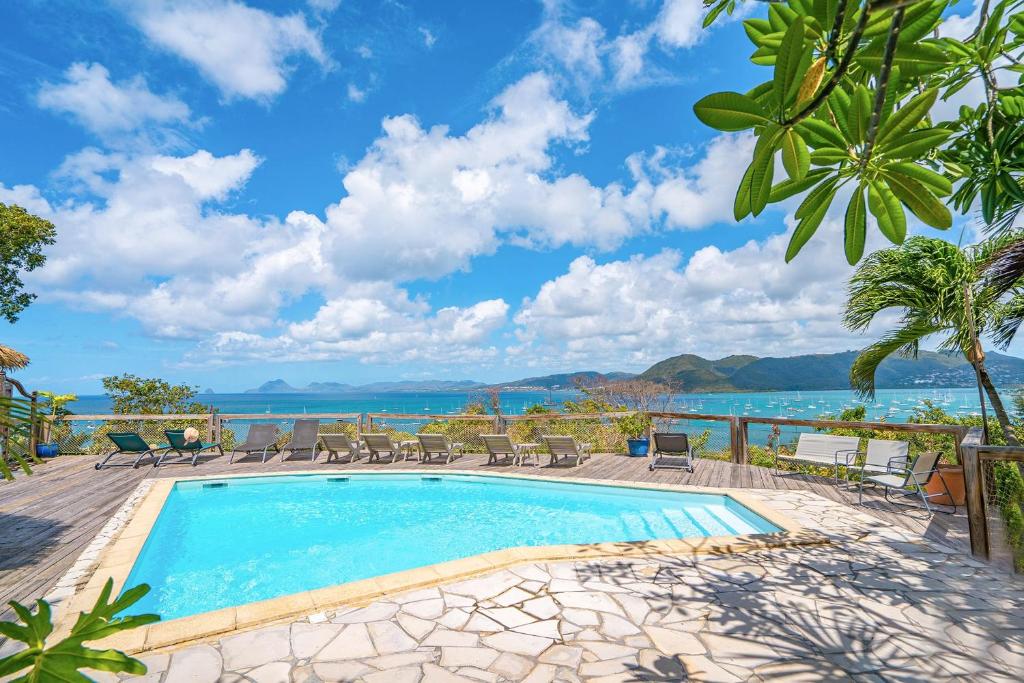 une piscine avec des chaises et l'océan en arrière-plan dans l'établissement Ty Paradis Magnifique Lodge pour un couple, à Sainte-Anne