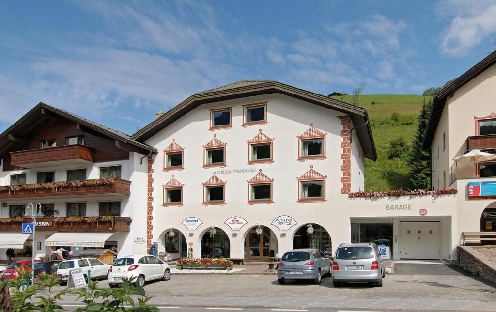 un gran edificio con coches estacionados en un estacionamiento en Cësa Panaval Apartments, en Santa Cristina Valgardena