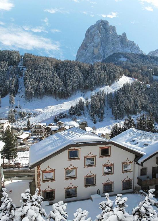 a snow covered building with a mountain in the background at Cësa Panaval Apartments in Santa Cristina in Val Gardena