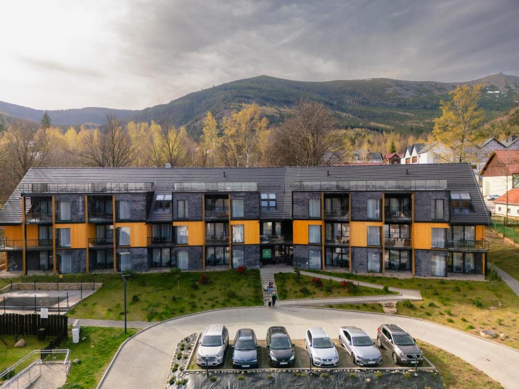 ein Apartmenthaus mit Autos auf einem Parkplatz in der Unterkunft Green Apartments Wilcza in Karpacz