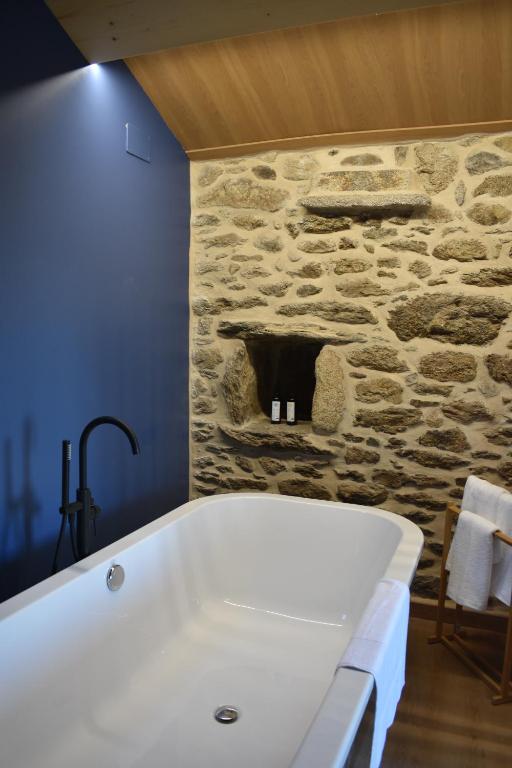 a bath tub in a bathroom with a stone wall at Cabana de Pili in A Estrada