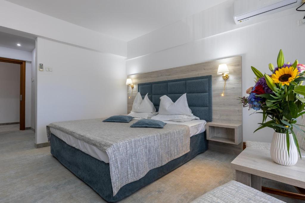 a hotel room with a bed and a vase of flowers at Hotel Condor in Mamaia