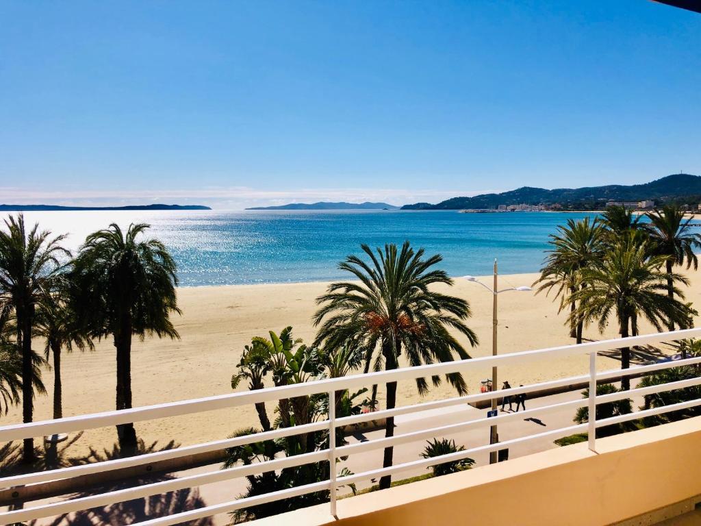 Una vista de la playa desde el balcón de un resort. en Appartement T3 lumineux traversant totalement neuf en face de la plage Front de mer vue sur les iles Vue mer panoramique assurée Résidence de la plage centre ville du Lavandou 3eme étage avec ascenseur Appartement T3, en Le Lavandou