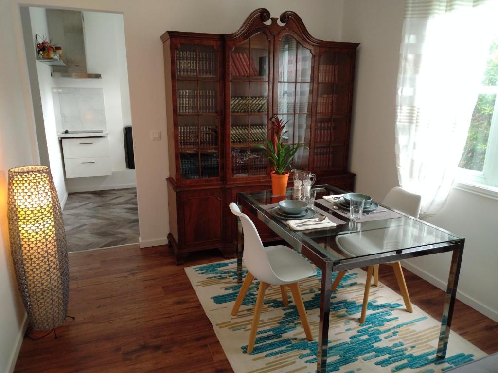 uma sala de jantar com uma mesa de vidro e cadeiras brancas em Appartement indépendant Ô Bohème em Fourqueux