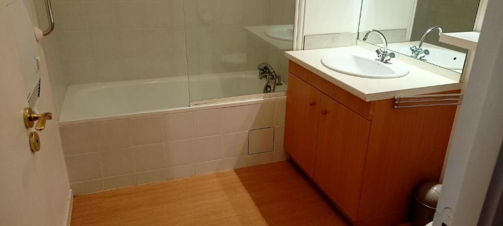 y baño con lavabo, bañera y espejo. en LA MARMOTTE appartement T2 classé 3 étoiles, en Aulus-les-Bains