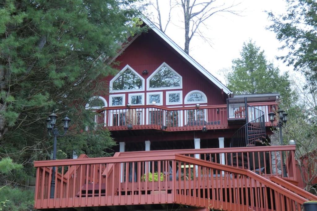 a large red house with a large deck at Catskills Lakefront Escape with Hot Tub in Monticello