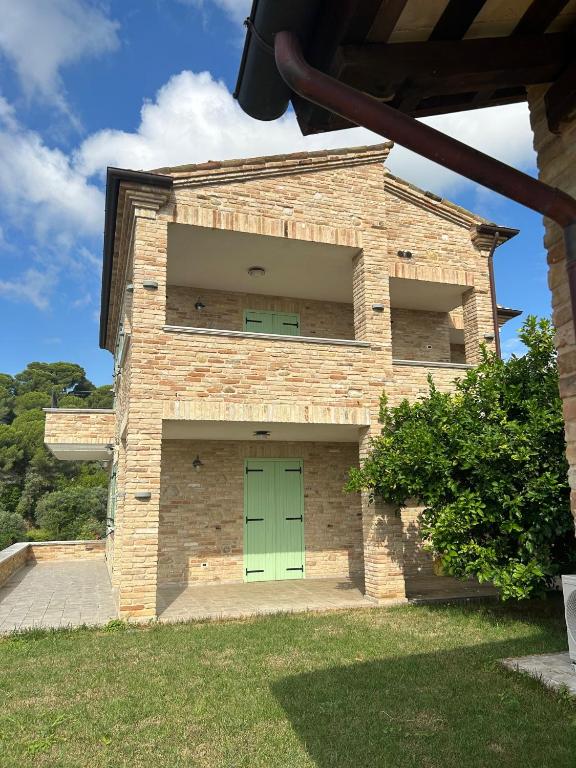 a brick building with a green door in a yard at Villa Colle dei Pini in Cupra Marittima