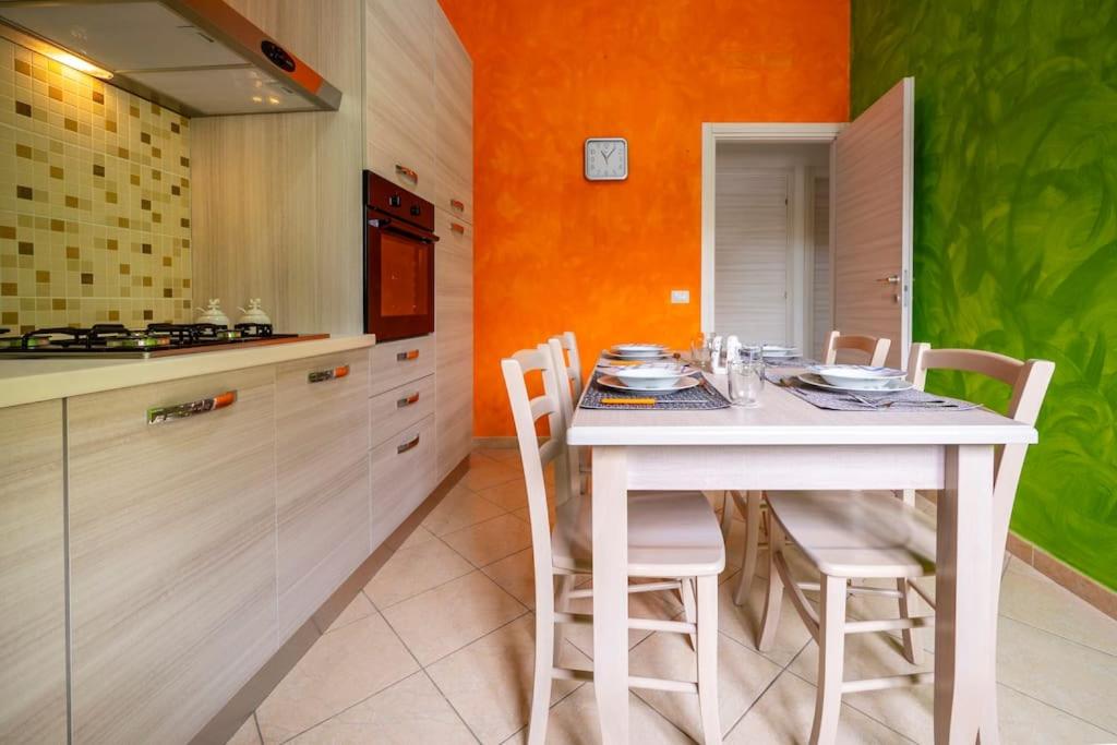 uma cozinha com uma mesa branca e cadeiras em Avola house orange em Avola