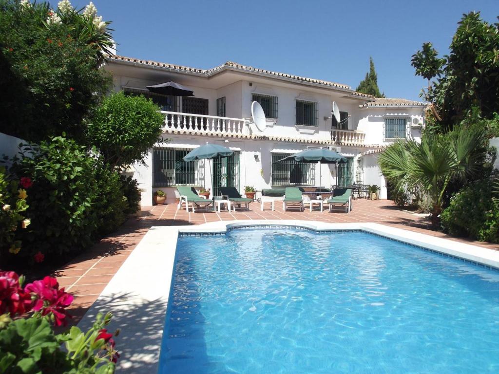 a villa with a swimming pool in front of a house at Casa Ladera in Las Lagunas Mijas