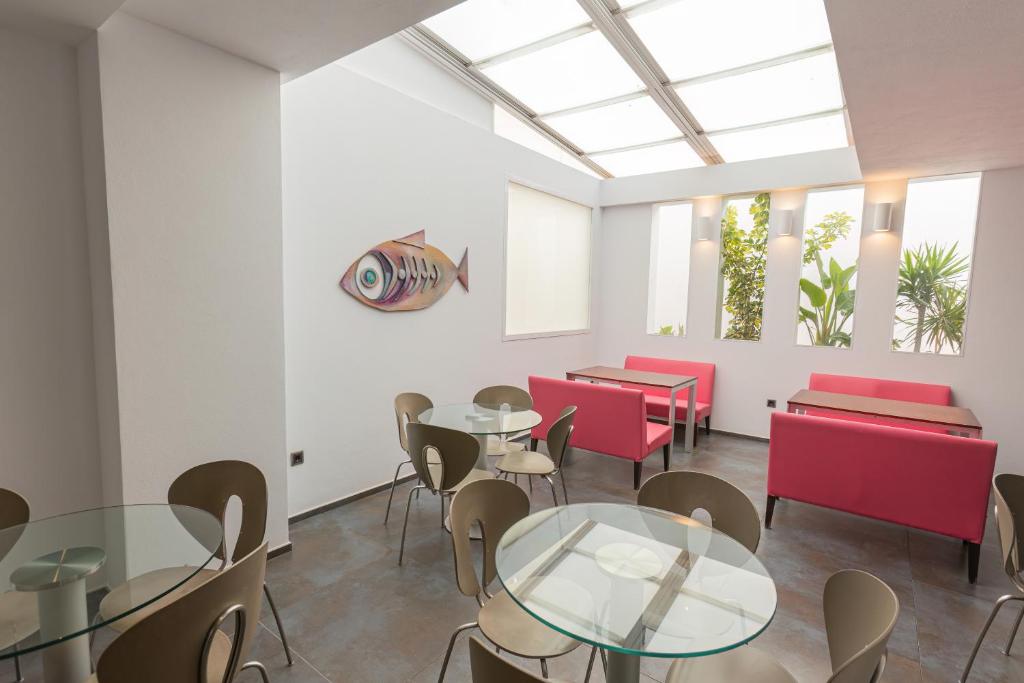 a dining room with tables and chairs and windows at Hotel Adiafa in Barbate