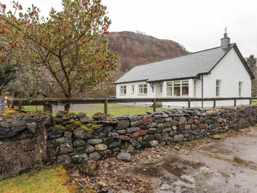 a stone wall in front of a white house at Tigh na Drochit in Glenelg