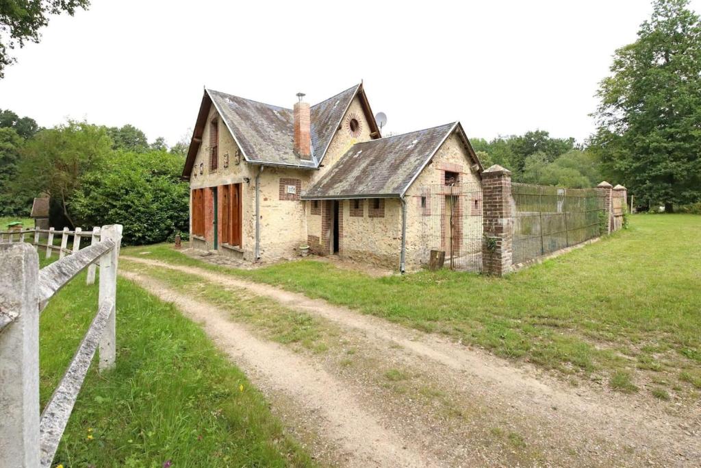 una casa vieja en un camino de tierra junto a una valla en Maison de 3 chambres avec jardin amenage et wifi a Raizeux, en Raizeux