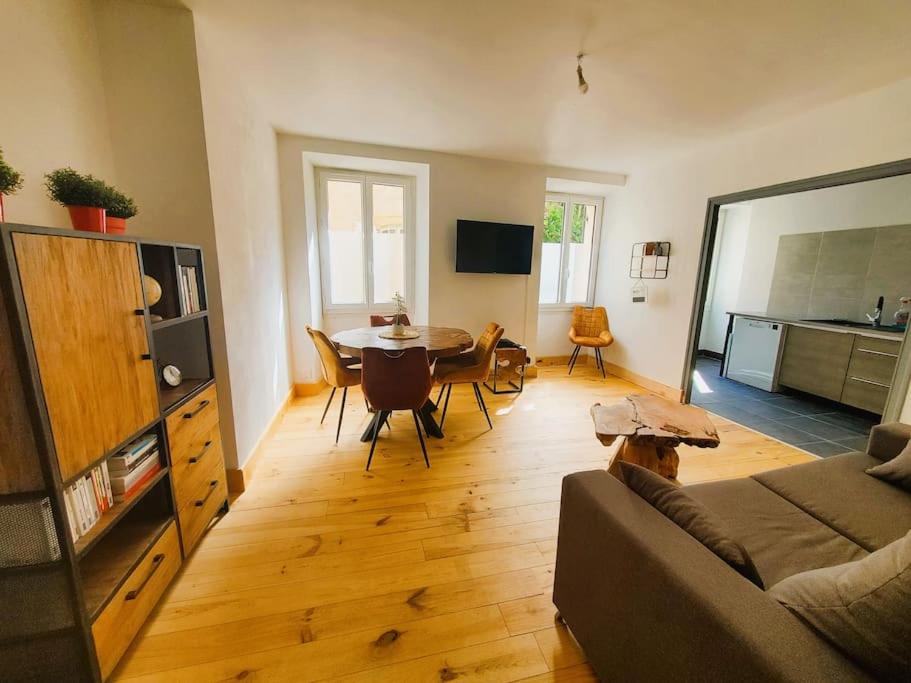 ein Wohnzimmer mit einem Sofa und einem Esstisch in der Unterkunft Appartement climatisé avec extérieur à Sarlat in Sarlat-la-Canéda