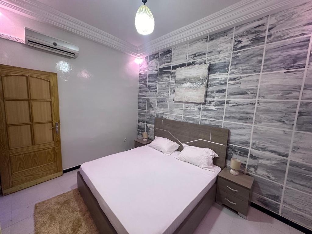 a bedroom with a bed and a stone wall at Welltima Teranga in Dakar