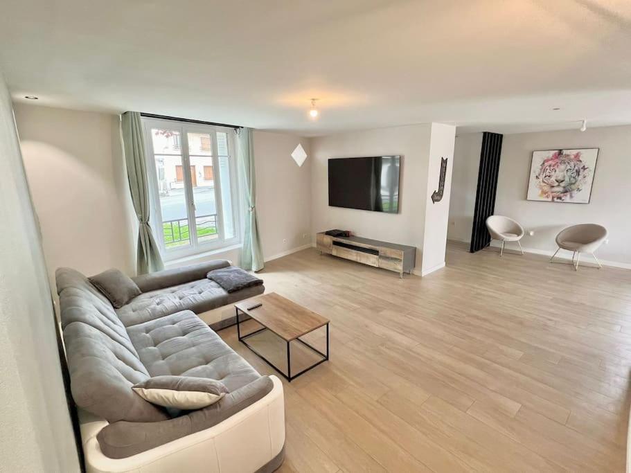 Il comprend un salon doté d'un canapé et d'une télévision à écran plat. dans l'établissement Luxurious cozy house 10 minutes from Charles de Gaulle Airport, à Tremblay-en-France