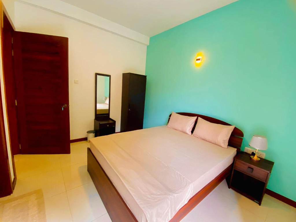 キャンディにある`Kandy Lake Round Apartmentの青い壁のベッドルーム1室(ベッド1台付)