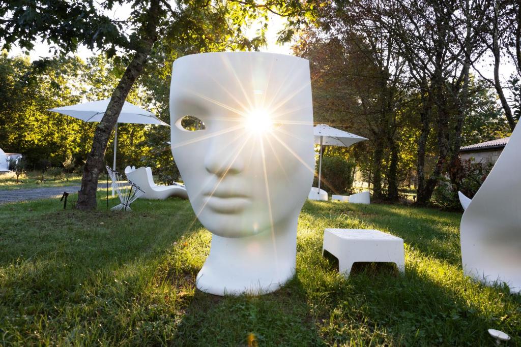 una scultura bianca di un viso con il sole in un campo di L ost in Sensations -Hébergements Insolites et Suites de luxe Spa Sauna Piscine Forêt a Marcenas