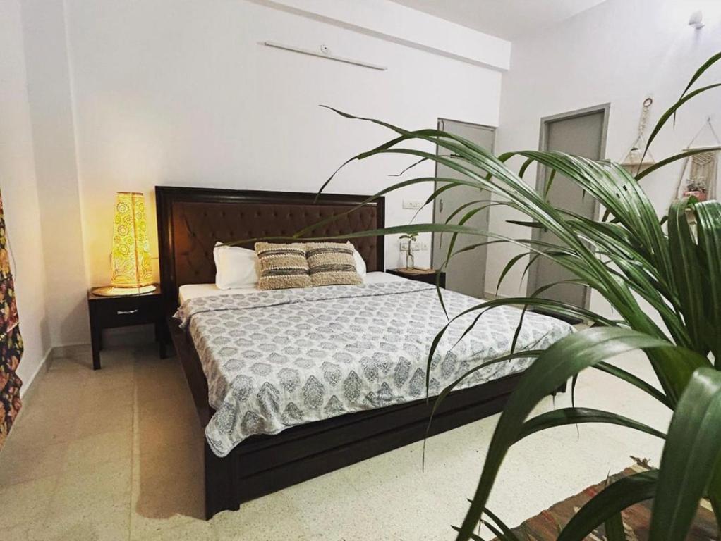 a bedroom with a bed with pillows and a plant at Solanki farms & Pool Villa garden fully private in Jaipur