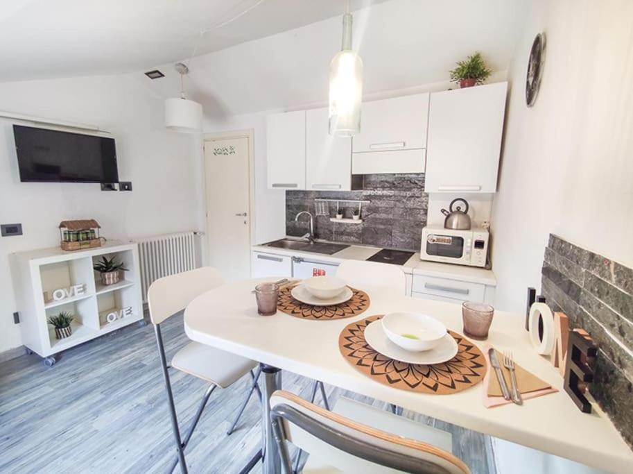 eine Küche mit weißen Schränken und einem Tisch mit Tellern darauf in der Unterkunft Mansarda Balilla Centralissima vicinissima al mare in San Benedetto del Tronto