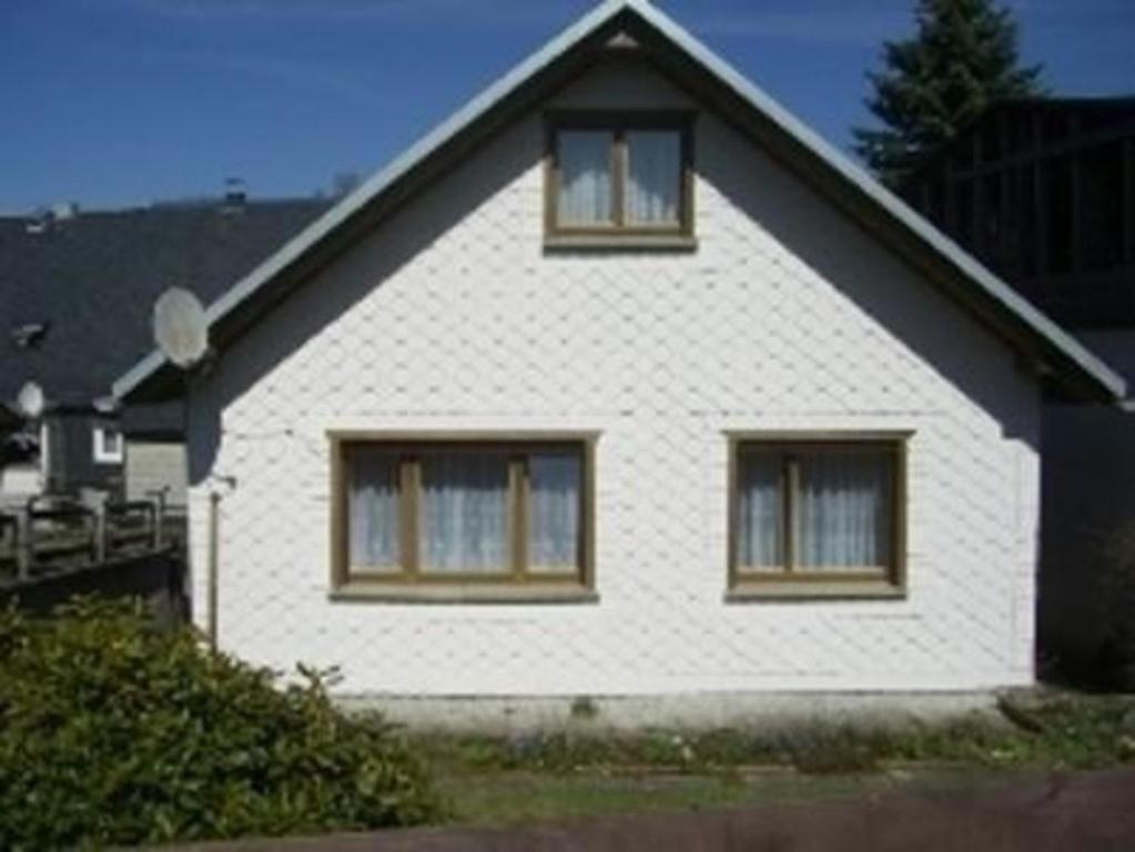 Una casa blanca con tres ventanas en el costado. en Freistehendes Ferienhaus in ruhiger Lage - b58107 en Großbreitenbach