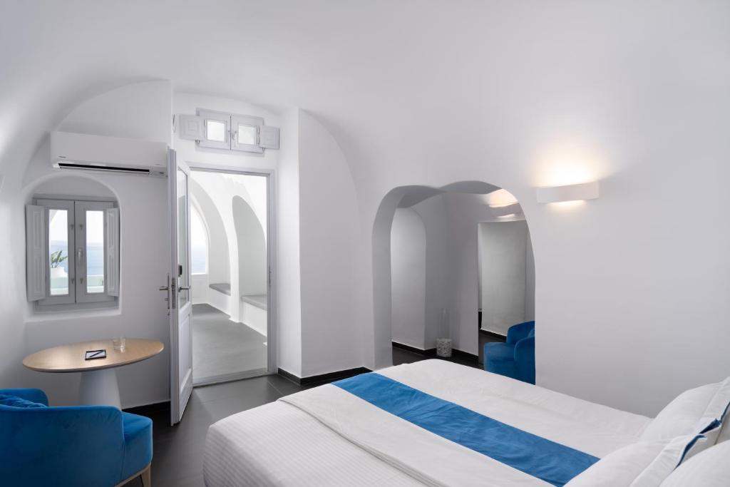 伊亞的住宿－Katikies Villa Santorini - The Leading Hotels Of The World，卧室配有白色的床和蓝色椅子