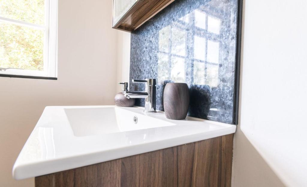 baño con lavabo blanco y ventana en The Cherry Tree Inn en Ticehurst