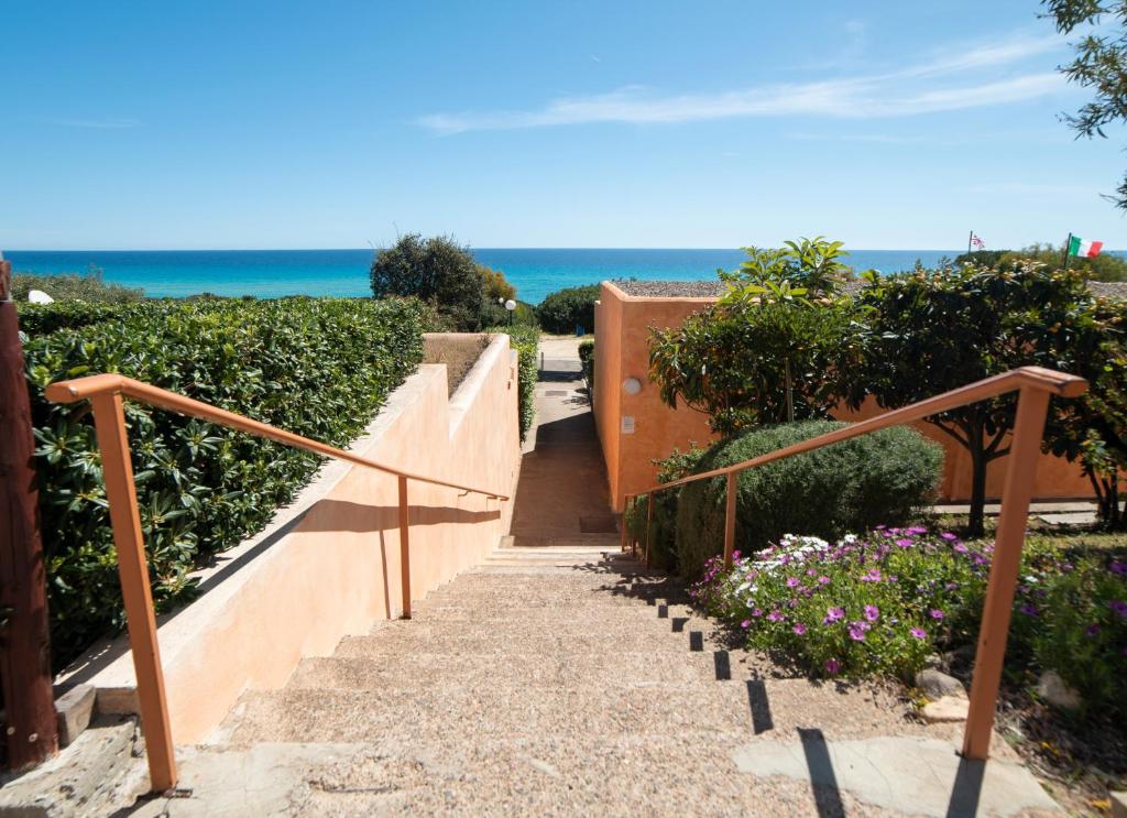 a stairway leading down to the beach with flowers at Monolocale Free Beach Residence due passi dal mare in Costa Rei