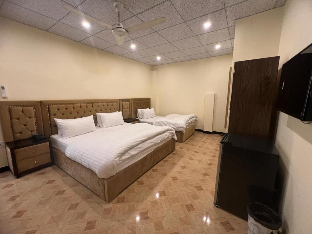 a bedroom with two beds and a television in it at Cozy Cottage Islamabad in Islamabad