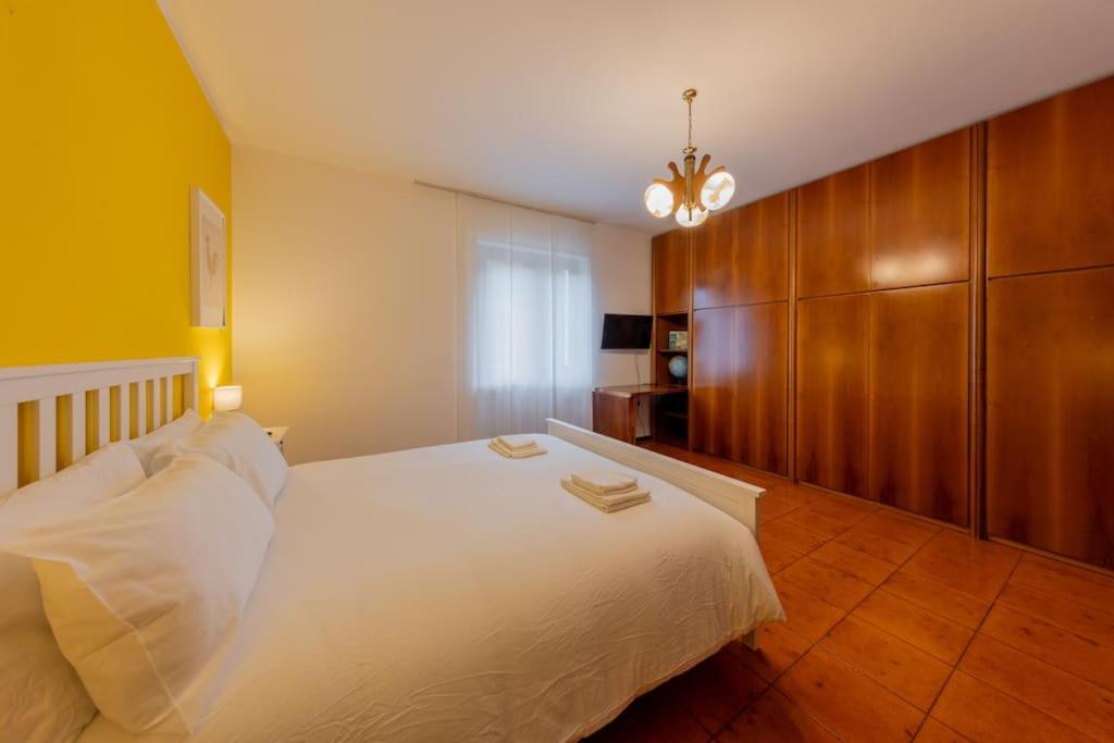 una camera con letto bianco e lampadario pendente di La Terrazza sui Monti a Castiglione dʼIntelvi