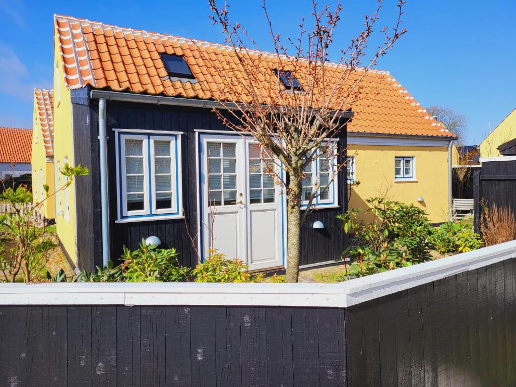 een klein huis met een zwart hek ervoor bij Tinghus Flat in Skagen