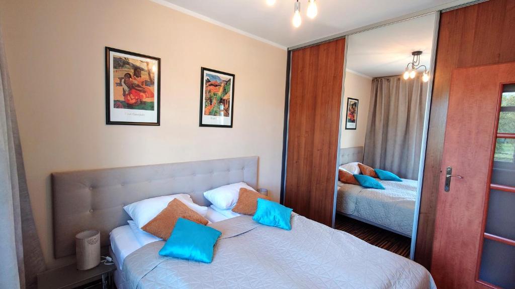 a bedroom with a bed with blue pillows and a mirror at Apartament Modern Life w centrum z parkingiem in Jelenia Góra
