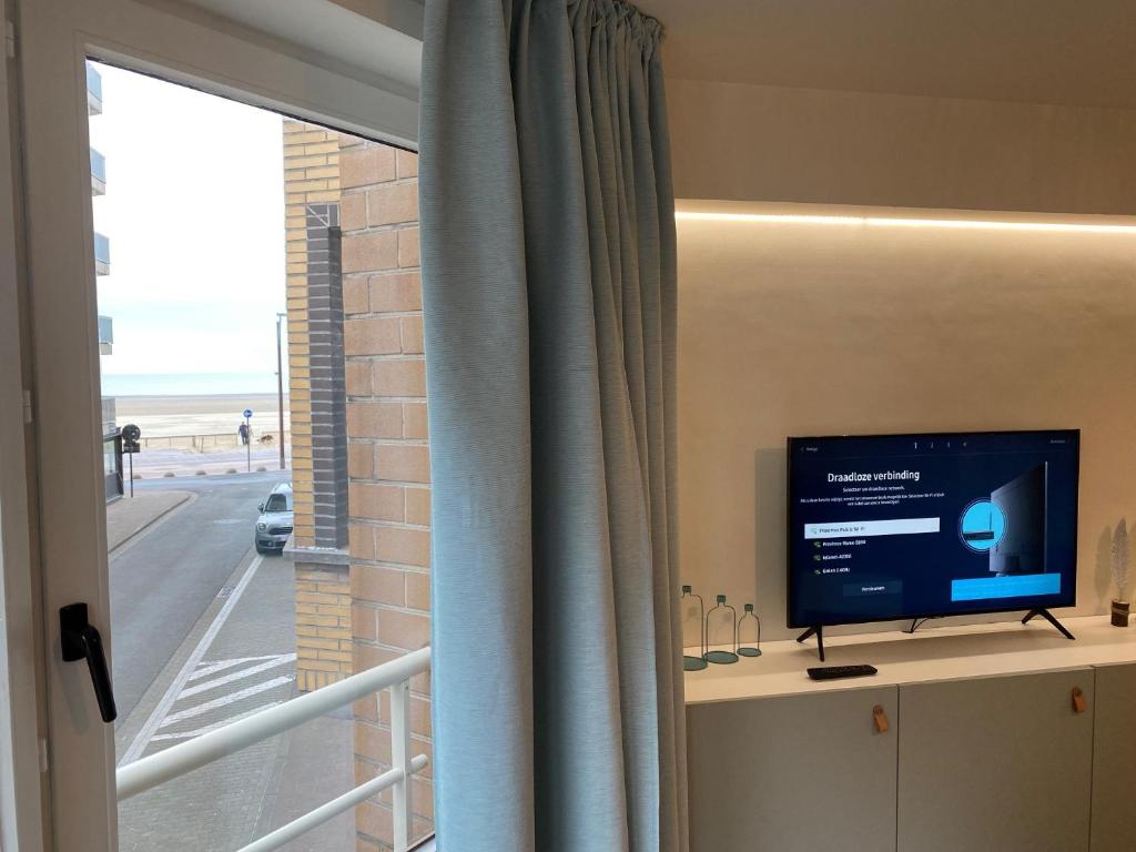 a flat screen tv sitting on a shelf next to a window at Tof en ruim appartement in Heist-Aan-Zee! in Knokke-Heist