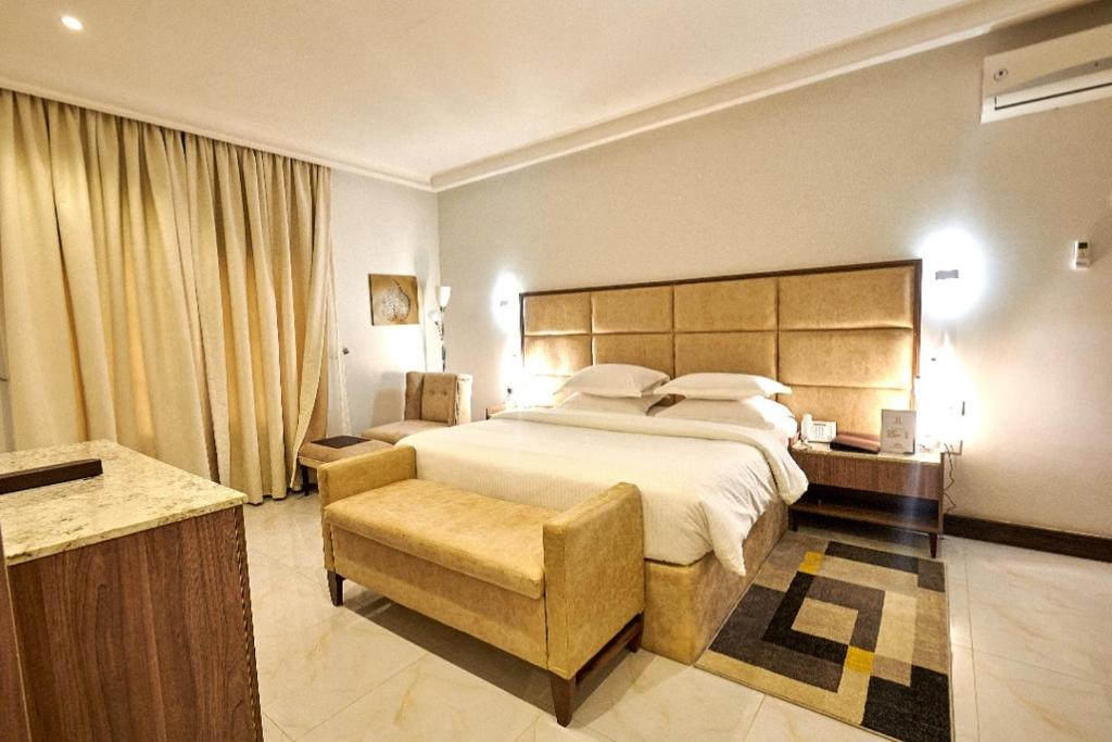 MEETHAQ HOTELS MAITAMA في أبوجا: غرفة فندقية بسرير كبير وكرسي