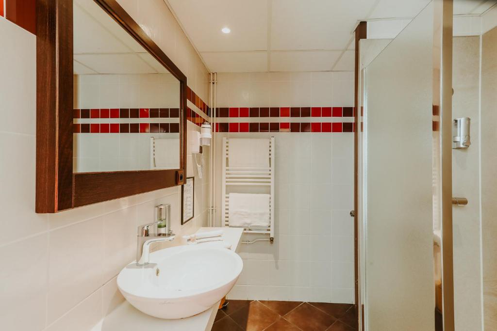 a bathroom with a white sink and a shower at Hôtel L&#39;Iroko The Originals City in Aix-les-Bains