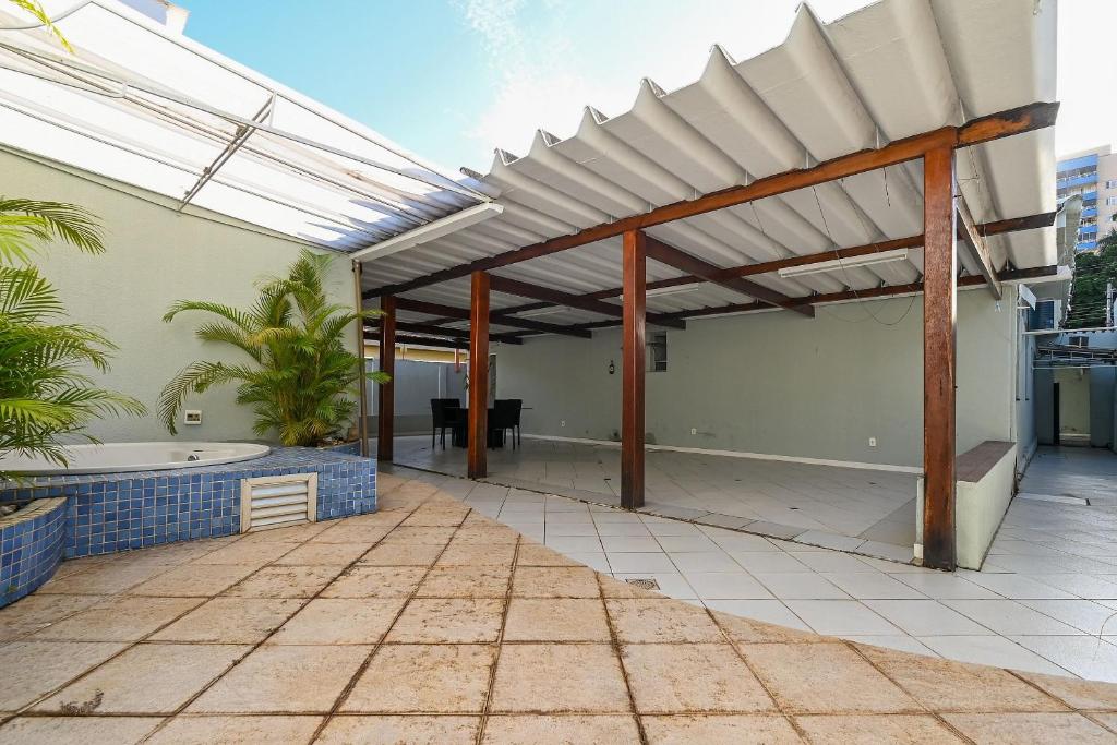 Casa Espaçosa com Jacuzzi e Churrasqueira RAU409 في غويانيا: فناء في الهواء الطلق مع شمسية على منزل