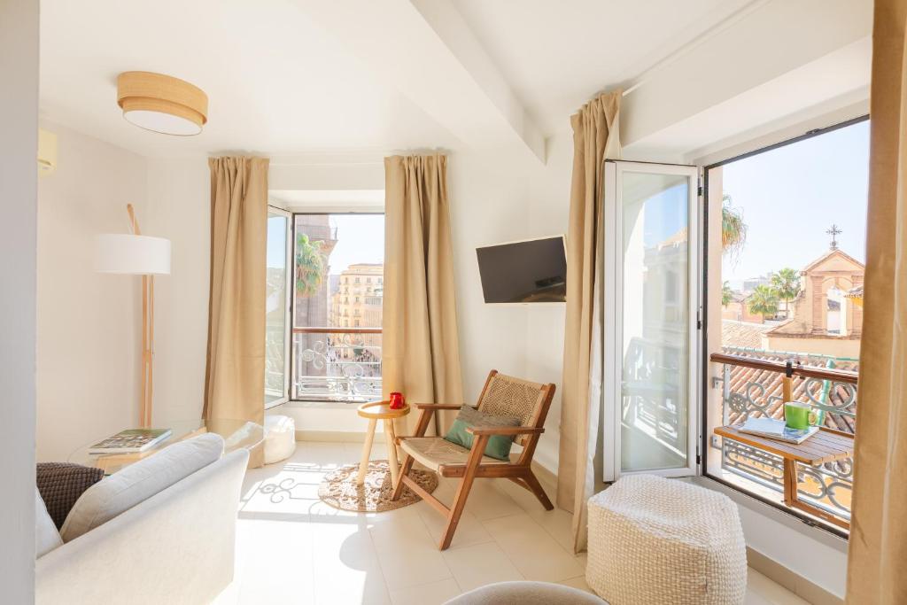 uma sala de estar com um sofá e uma grande janela em Balcón de la Catedral em Málaga