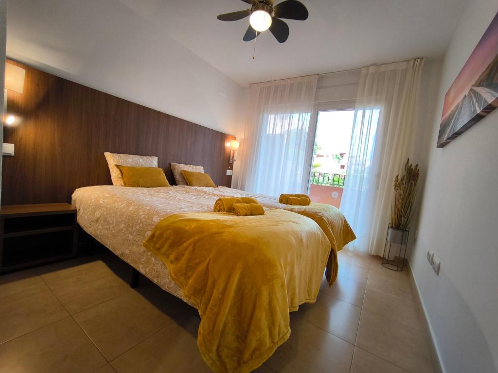 a bedroom with a large bed with a yellow blanket at Casa Amarillo Mar Menor Golf Resort in Murcia