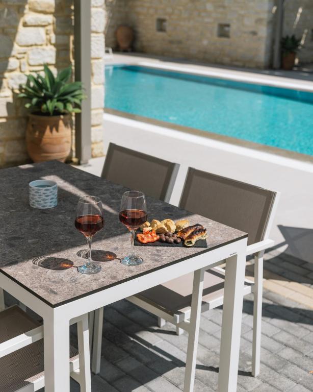 a table with two glasses of wine and a plate of food at Matala Prime Villas in Matala