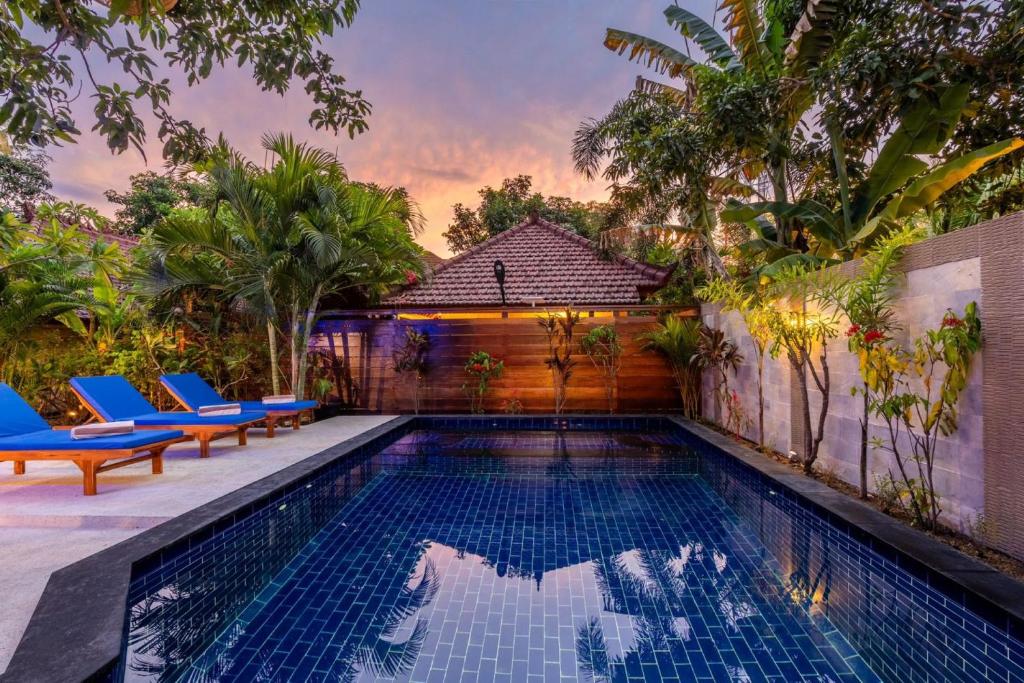 a swimming pool with two blue chairs and a house at Paradise Luxury Villa in Gili Air