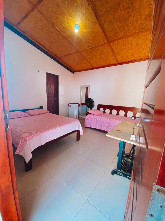 a bedroom with two beds and a wooden ceiling at Flechimar Suítes in Trairi