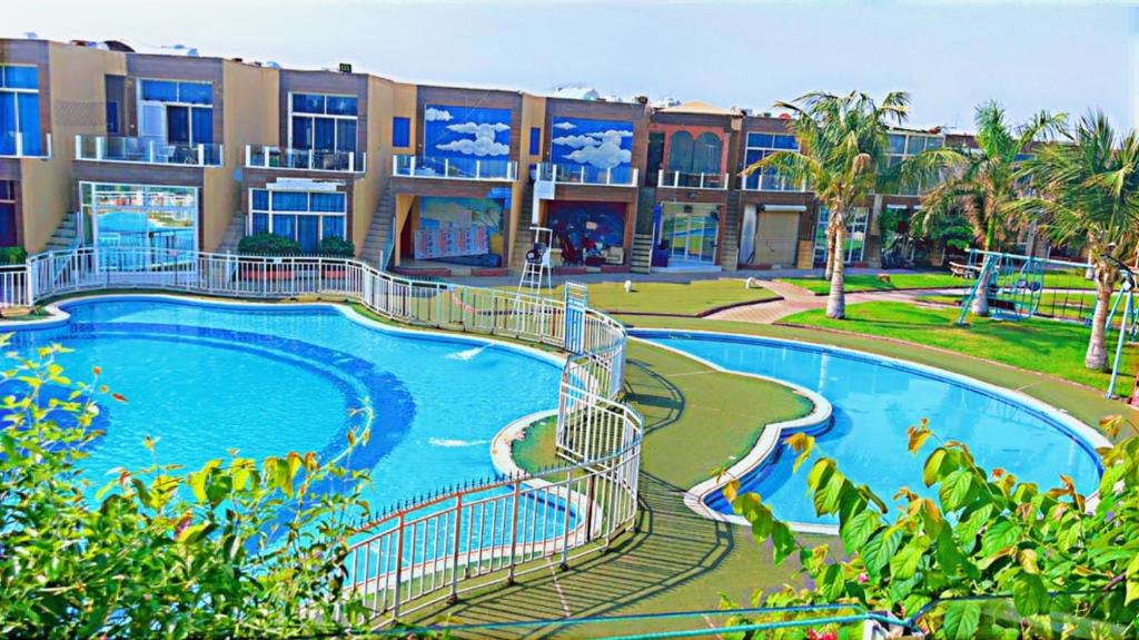 a resort with a large swimming pool with a slide at شقه غروب البحر in Obhor