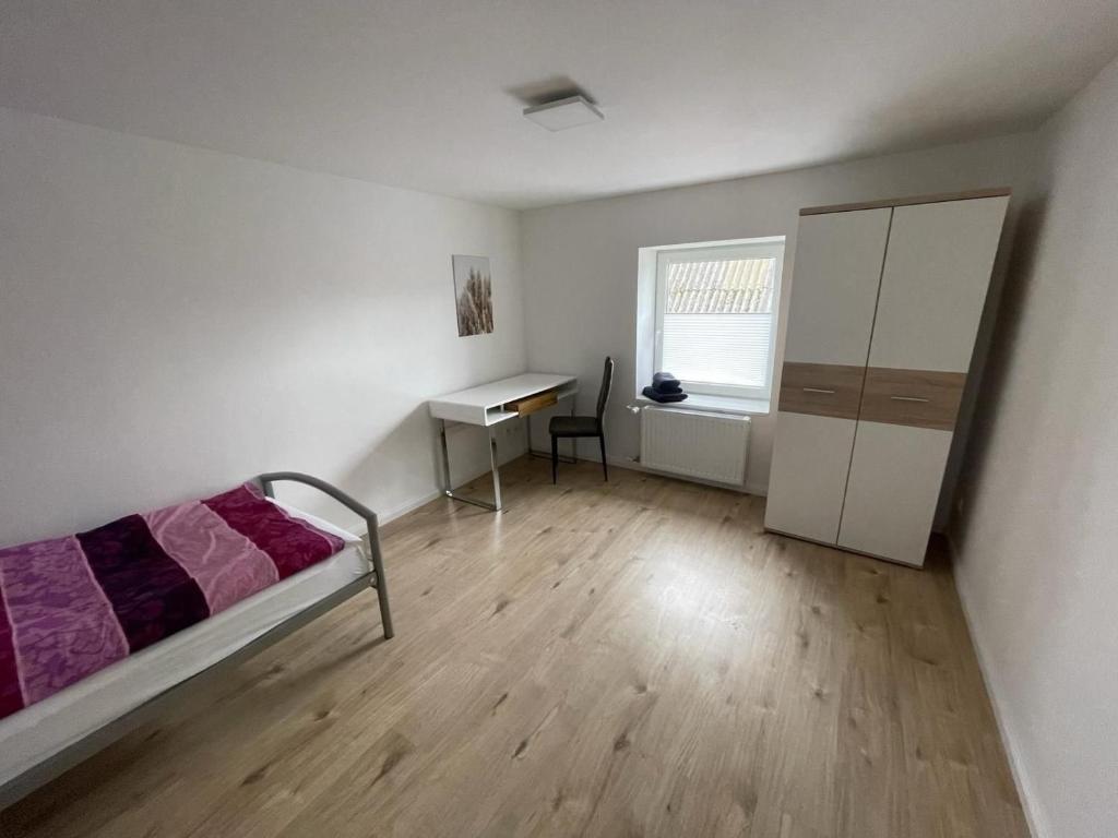 1 dormitorio con cama, escritorio y ventana en Gemütliches Einzelzimmer in Groß Vollstedt - zentral gelegen ideal für Monteuere u Reisende, Gemeinschaftsbad Einzelzimmer 2, en Groß Vollstedt