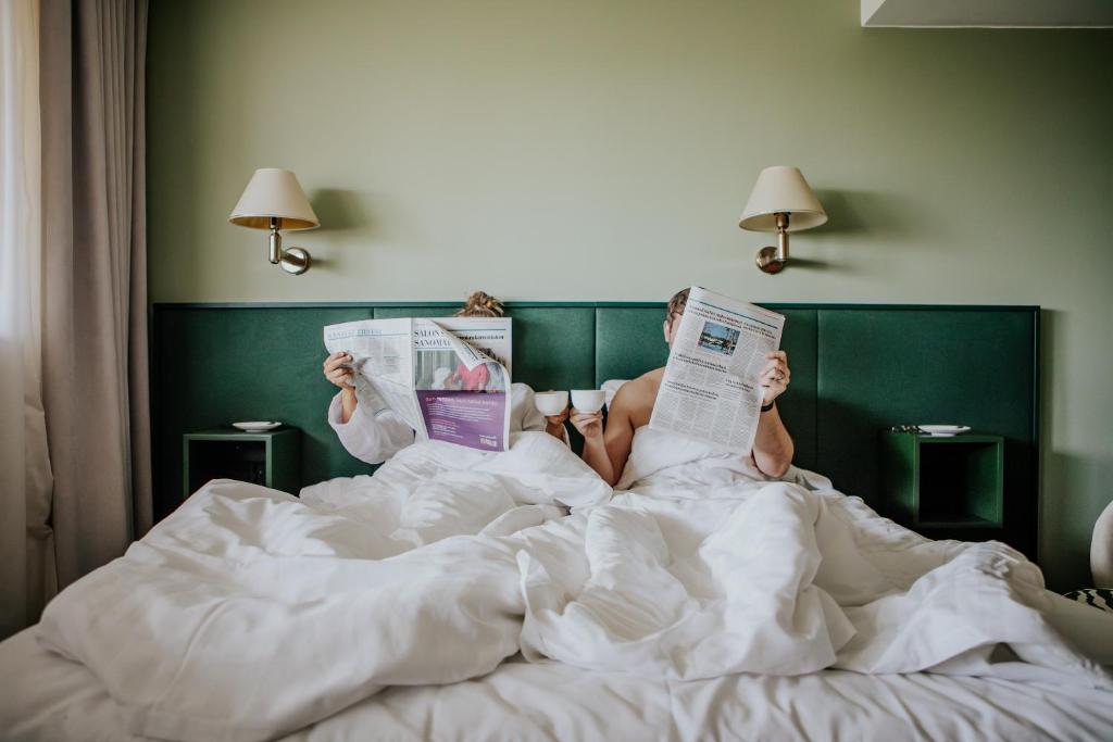 una persona acostada en la cama leyendo el periódico en Hotel Fjalar, en Salo
