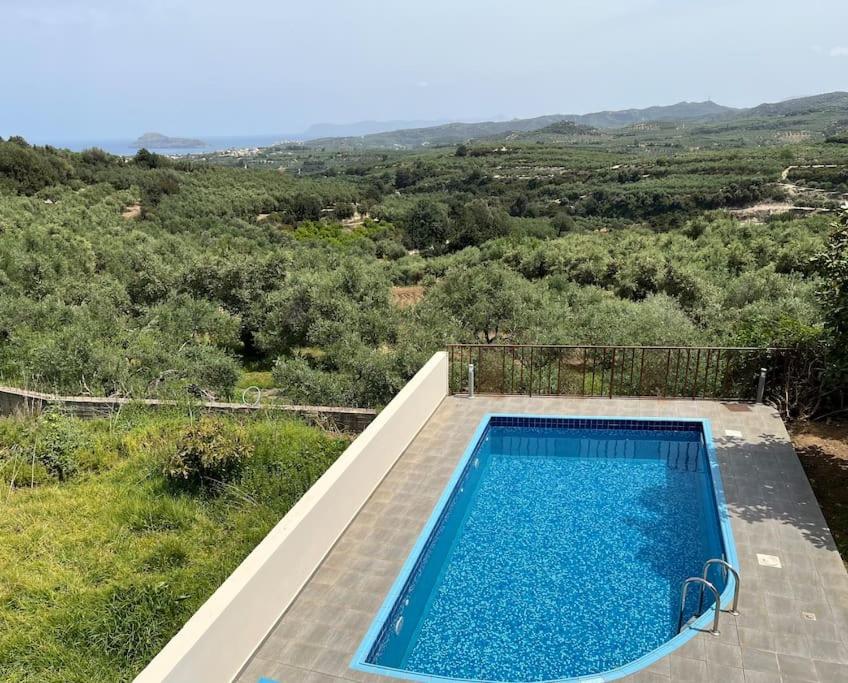 a swimming pool with a view of a field at Ion villa - Xirokampi in Ayiá