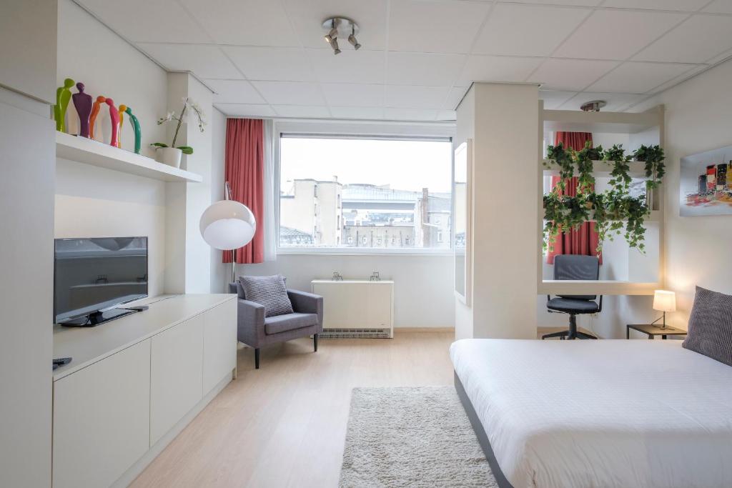 um quarto com uma cama, uma televisão e uma cadeira em Beau studio dans le Centre de Bruxelles em Bruxelas