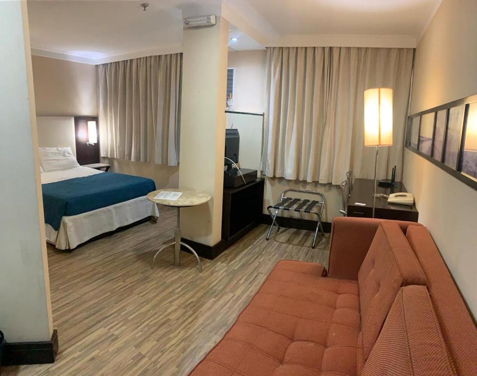 ein Hotelzimmer mit einem Bett und einem Sofa in der Unterkunft Charmoso Flat na Alameda Santos in São Paulo