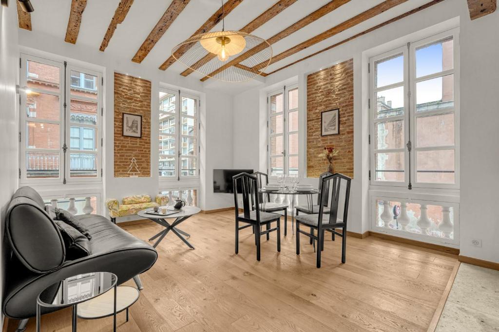 un salon avec une table, des chaises et des fenêtres dans l'établissement Mess d'Yvonne - 45m2 en plein cœur de Toulouse, à Toulouse