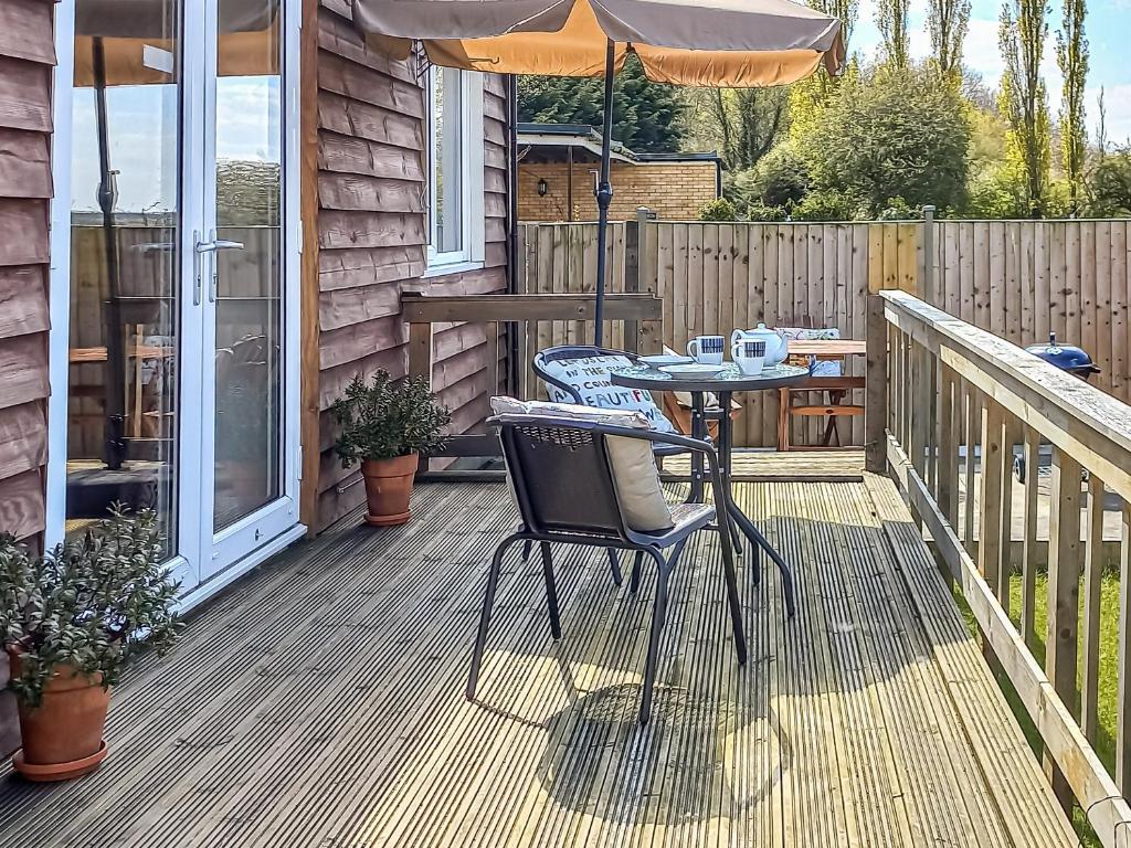 a table and chairs on a deck with an umbrella at Limewood Lodge in Kingthorpe