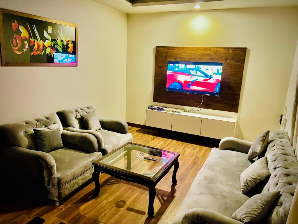 ein Wohnzimmer mit 2 Sofas und einem TV in der Unterkunft Luxe and Family-friendly 2BHK in Islamabad