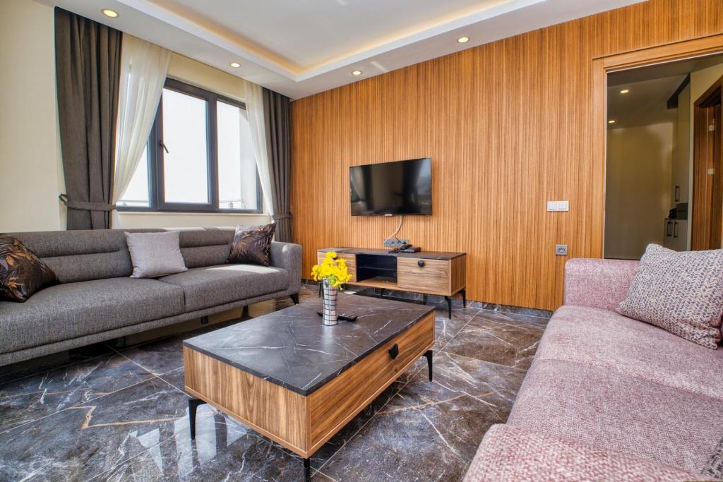 een woonkamer met 2 banken en een tv bij Evin Park Suit Lara in Aksu